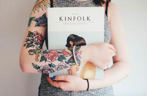 Woman with colorful tattoo, holding "Kinfolk" magazine in the hands