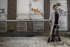 Woman on the old bicycle, near the building, with the colorful graffities