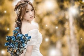 bride with blue bouquet on blurred background in forest