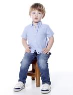 Cute, blonde child, sitting on the wooden chair, at white background