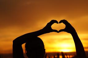 Love, heart gesture at sunset sky