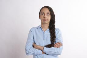 Portrait of a confused woman, with the arms crossed, at white background