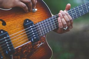 Musician with the ring, playing on the beautiful, colorful, wooden, gradient guitar