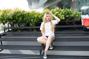 Girl in white T-Shirt sits outdoor