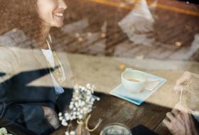 View of the couple drinking coffee in the cafe, through the window