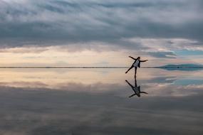 Woman, standing on the beautiful waterscape, with the reflections of the colorful and beautiful sunset in the clouds