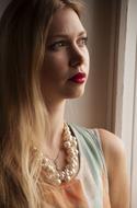 serious young Woman with pearl necklace at window