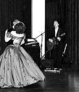 black and white photo of a dancing couple and a musician with a microphone