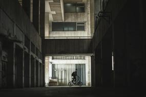 young boy riding bicycle in dark courtyard