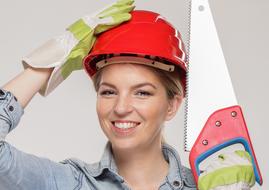 photo portrait of a girl in a construction helmet and a saw in hand