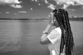 black and white photo of a girl with pigtails near the river