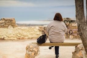 Woman Senior sitting on a bench near the water in Spain