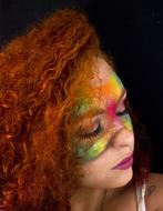 Portrait of the woman, with curly hair, and colorful mask, at black background