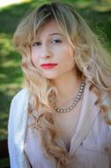 Portrait of the blonde woman, with the make-up and necklace, at blurred background
