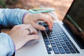 female hands on a laptop in nature on a blurred background