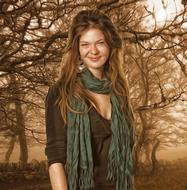 Portrait of the smiling woman, among the colorful plants, in sunlight