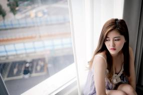 Portrait of the posing girl, near the window with light