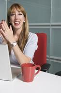 Portrait of a smiling, blonde woman with the laptop and red cup, in the university