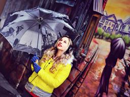 girl in a yellow jacket posing with an umbrella