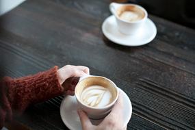 cup with Coffee in female hands on black table