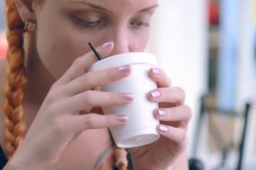 girl with a red braid and a cup of tea close-up on a blurred background