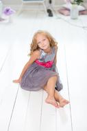 pretty caucasian child girl sits on white floor