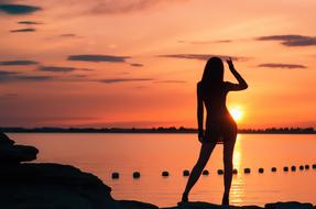 silhouette of a model near the water at dusk