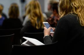 a girl writes a message on a smartphone at a seminar