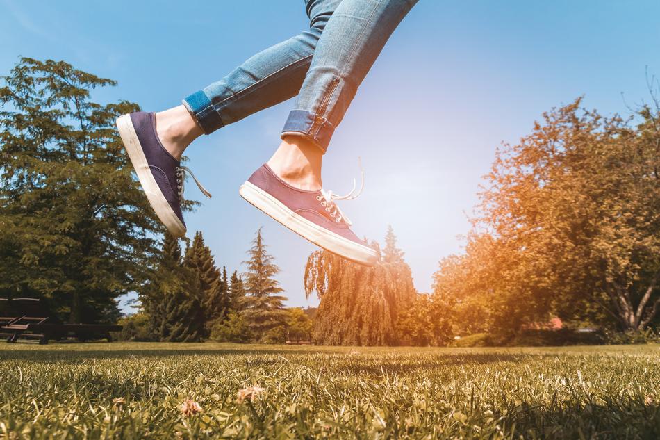 Legs of the jumping person, among the colorful and beautiful pants, at colorful sunlight in the sky