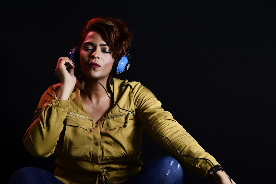 Portrait of the beautiful woman with blue headphones, listening to music, at blackground