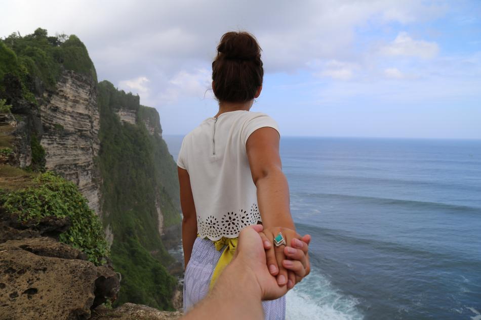 Couple, holding hands, on the beautiful and colorful cliff on the coast