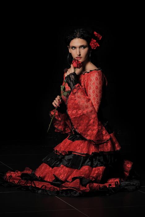Spanish Woman in red and black dress with rose in hands on black background