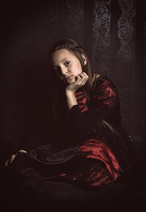 Portrait of the girl, in red clothing, posing among the darkness