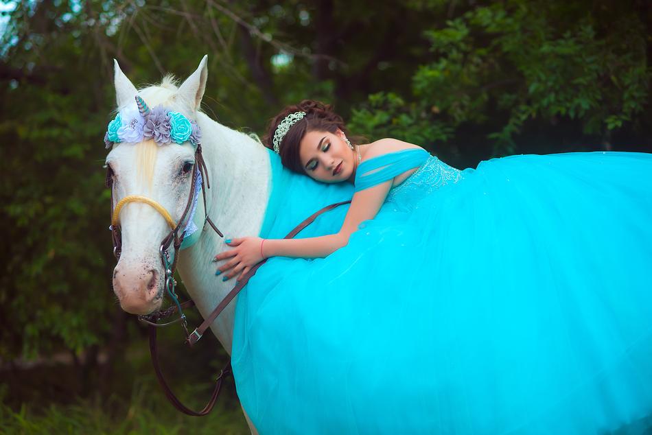 Woman in turquoise dress, with the beautiful and colorful unicorn horse, near the colorful plants