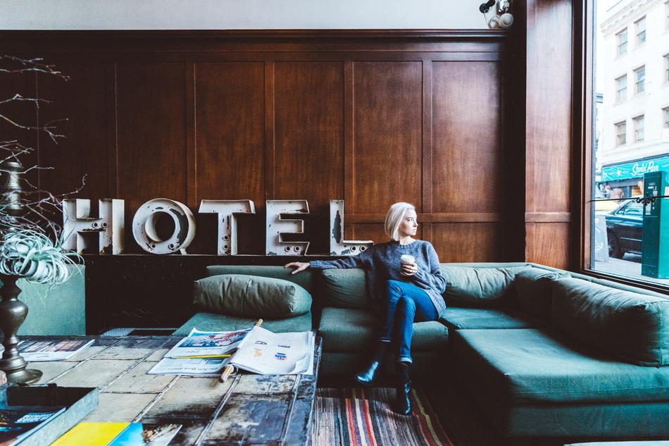 Woman with white hair, sitting on the beautiful sofa, in the room with 'HOTEL' sign