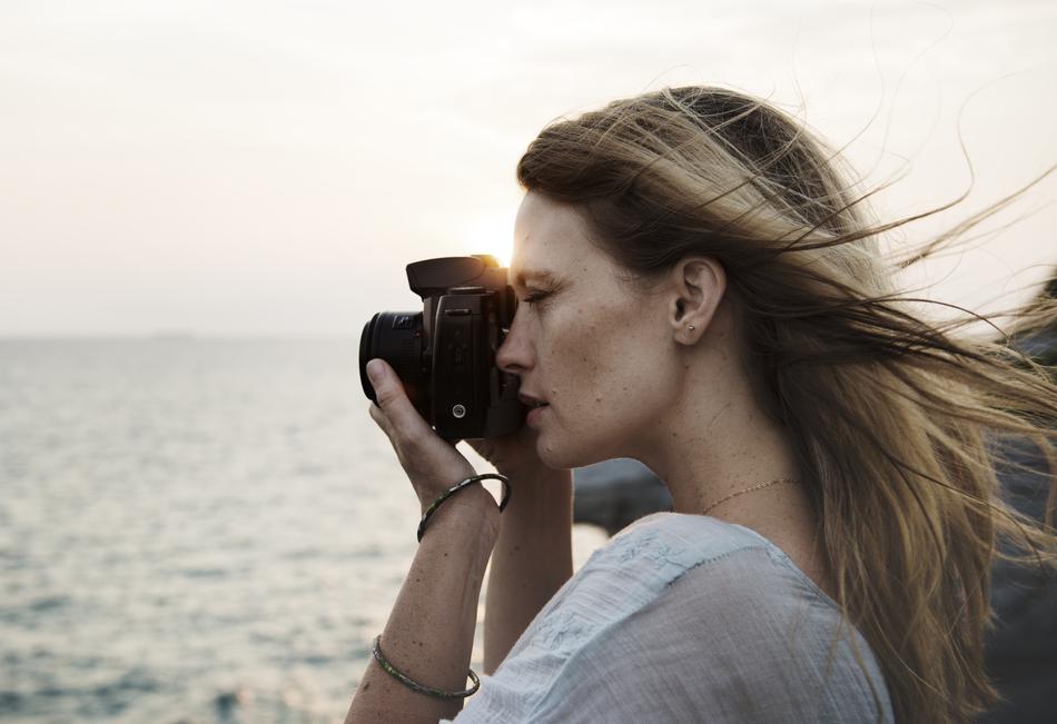 beautiful blonde with a camera near the water