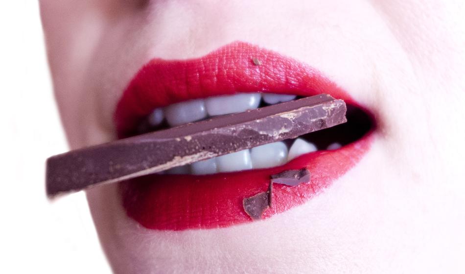 piece of chocolate between female teeth