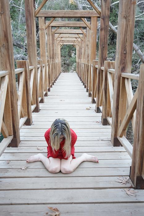depression, Woman in red cloth sits bended knees on wooden bridge