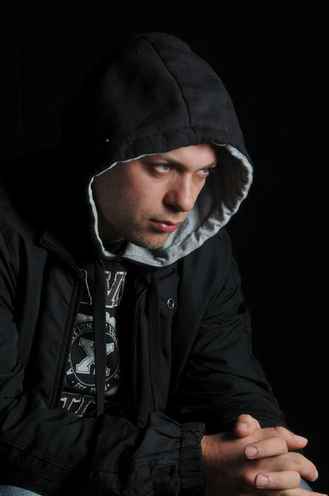 Portrait of the man, in the hoodie, holding hands together ,at black background
