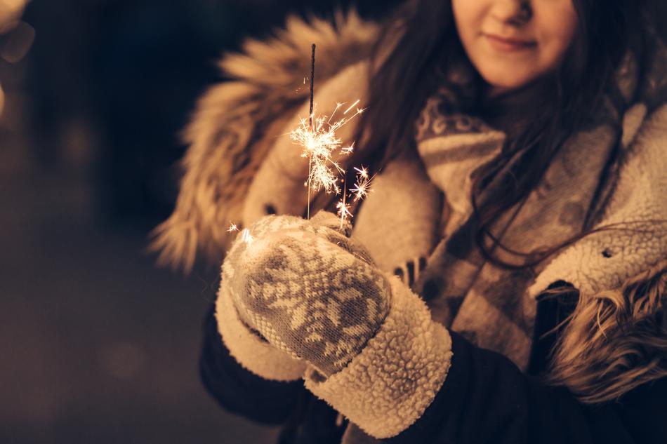 girl in mittens with sparkler on winter evening