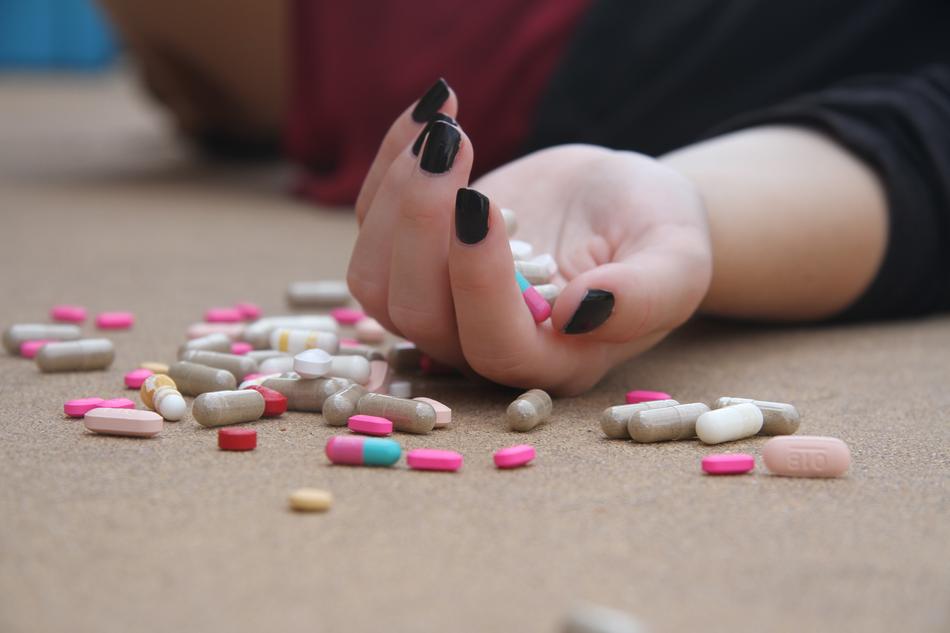 Laying person with colorful pills in the hand