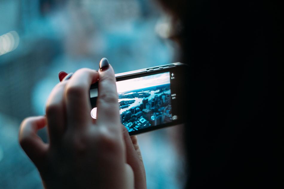 the girl looks at the photos in the smartphone