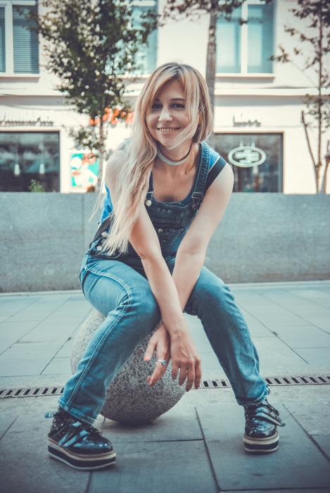 blonde sitting on a stone ball in the street
