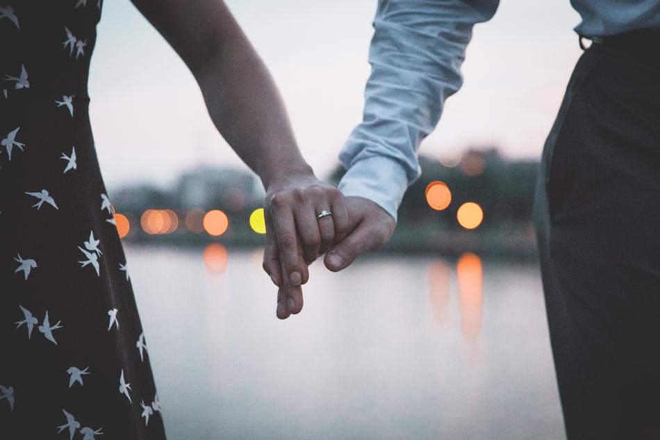 Couple, holding hands, on the beautiful coast with colorful bokeh lights