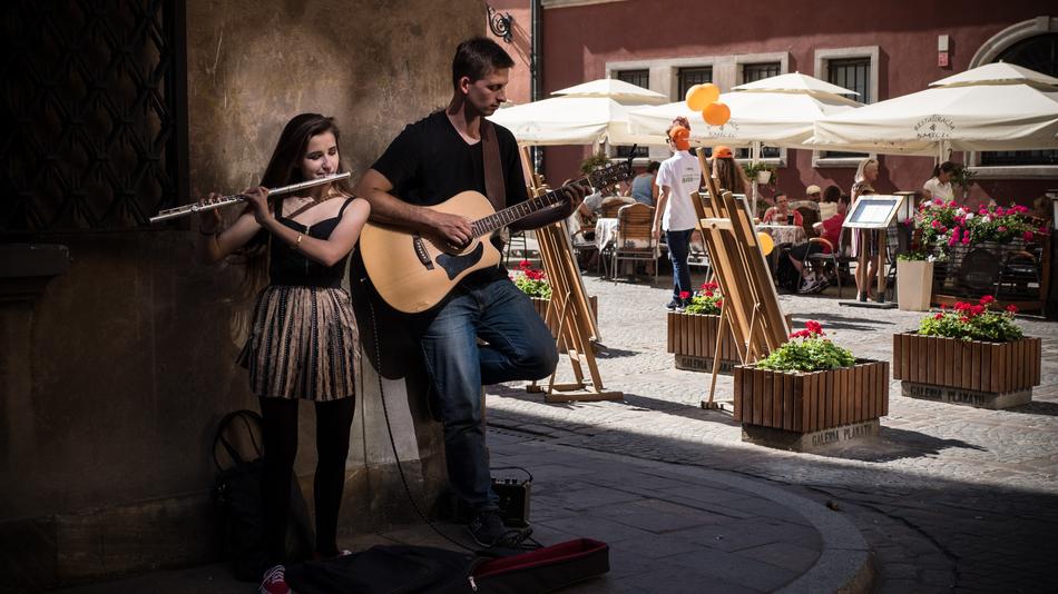 street musicians, young man and woman at wall in city