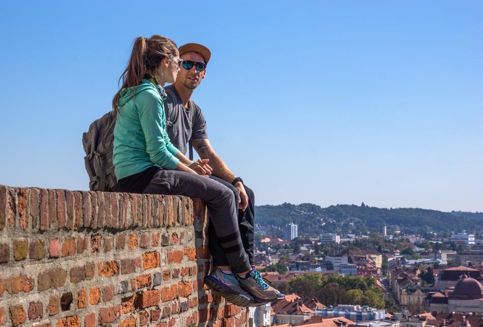tourists sit on a brick wall