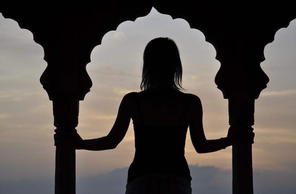 Silhouette of a woman, among the columns, at beautiful and colorful sunset, in India