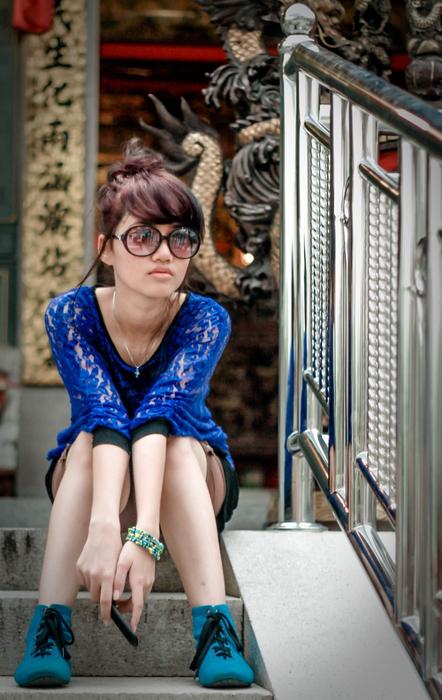 Beautiful girl in the blue clothing and glasses, posing on the stairs