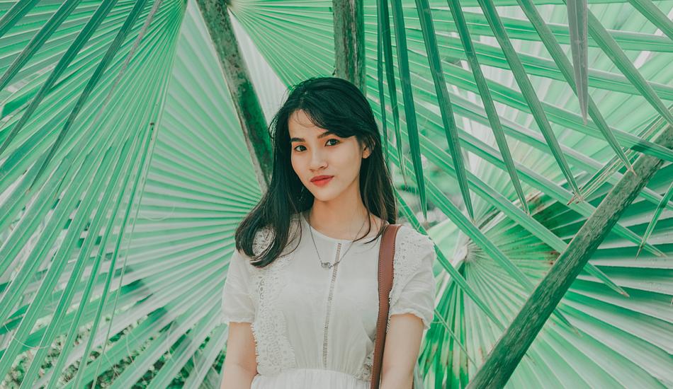 Portrait of Beautiful asian Girl at palm tree leaves