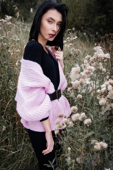 Portrait of the girl in pink sweater among the beautiful, white flowers